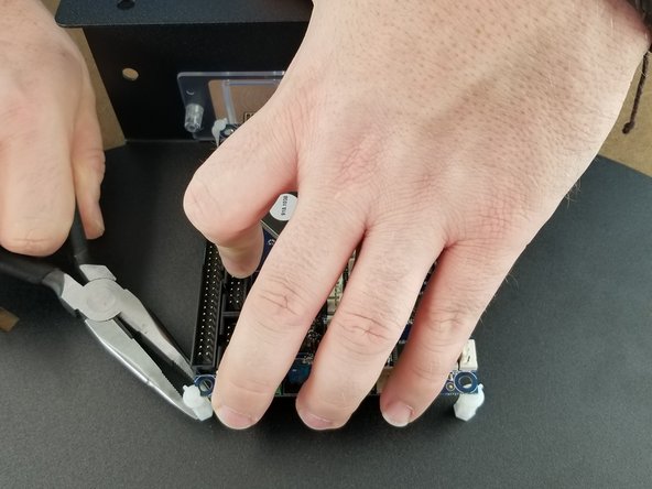 Using a pair of pliers, bend one of the tabs for the outer board support to insert the corner of the board into the support.