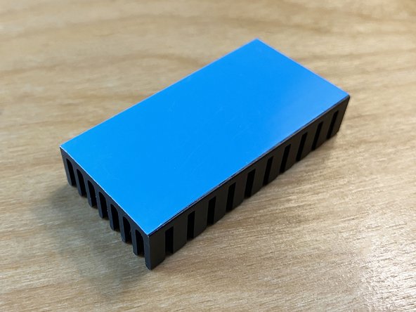 Flip the heatsink over and carefully remove the blue protective backing from the thermal pad, being careful not to touch the surface of the white adhesive with your fingers.
