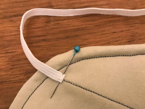 Take one 12" (30 cm) length of elastic band and pin it over one of the intersections between the sewn border line and one of the straight lines.