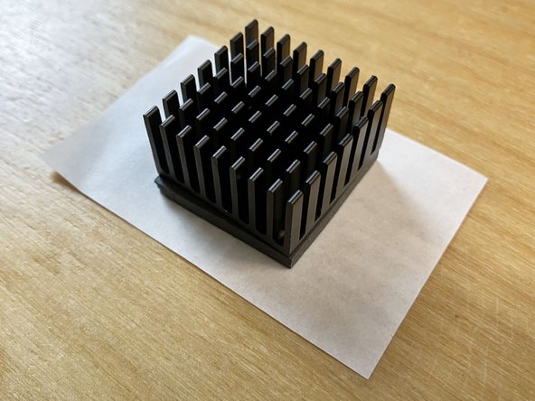 Place the heatsink down onto the center of the paper so that the gray thermal pad is touching the shiny side of the release paper. Press down lightly.