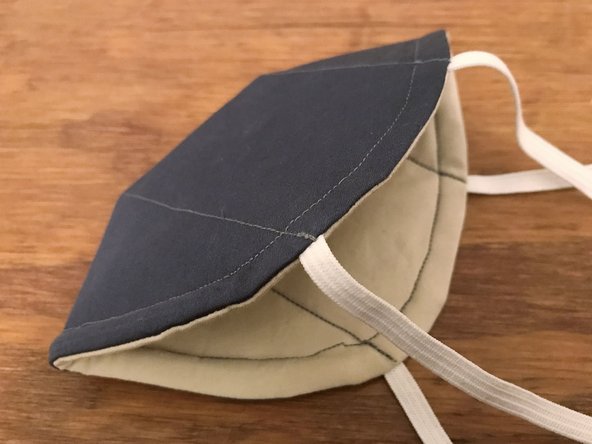Fold and flatten the mask in half, with the outside surface facing out.