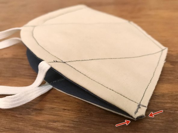 Diagonally trim a tiny bit of material from the bottom corner of the mask, as marked, being careful not to cut through any of the sewn seams.