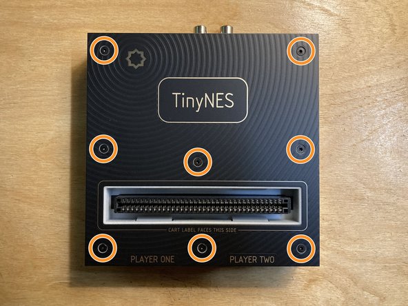 Place the TinyNES on a flat work surface. Make sure that nothing (including cables, controllers, or a cartridge) is connected to it. If the Cartridge Latch accessory is installed, please remove it.