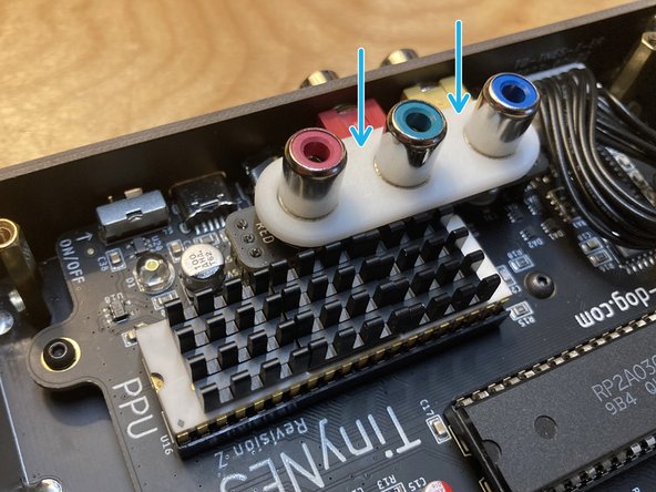 Place the white plastic spacer on top of the installed RGB board, with the RCA jacks going through the holes.