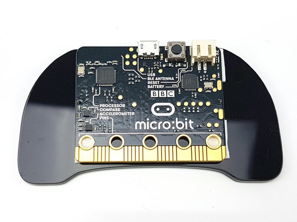 Peel the packing off of the 4 sticky squares, and stick the micro:bit onto the controller plate as shown in the picture.