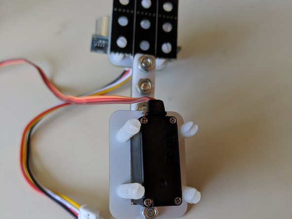 Using three standard size nuts and bolts from your construction kit, attach the ultrasonic sensor to the plastic beam.