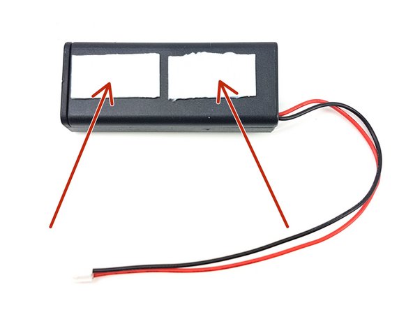 Take the other two sticky pads, and stick them onto the back of the battery pack (the side without a switch) as shown in the picture.