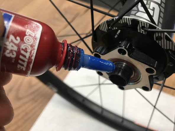 Add a small drop of medium strength thread locker to the threads of the axle.