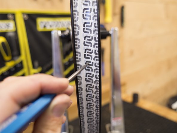 Using an awl or other pointy instrument, carefully poke a hole in the tape at the valve hole location.