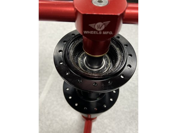 To install a new disc-side bearing, begin by gently centering the bearing in the bearing bore. Slide the bearing press drift onto the bearing press tool and insert through the disc-side of the hub. Slide the bearing drift onto the press tool on the non disc side, and install the handle.Tighten the tool to press in the disc-side bearing.