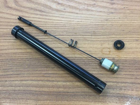 Push the cable holder from the bottom to slide the cam assembly out of the pillar