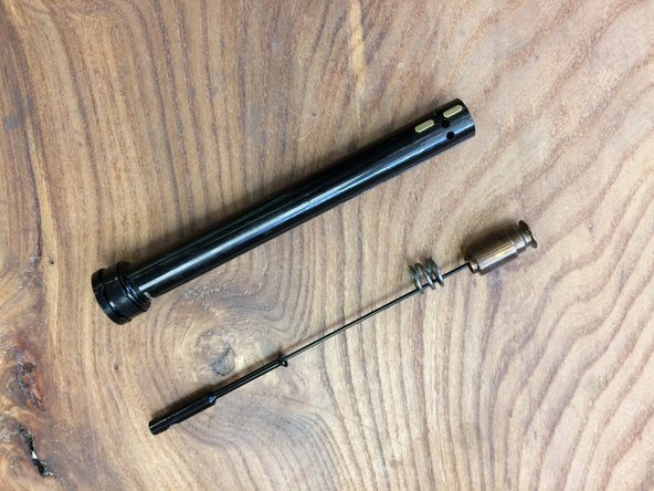 Push the cable holder from the bottom to slide the cam assembly out of the pillar