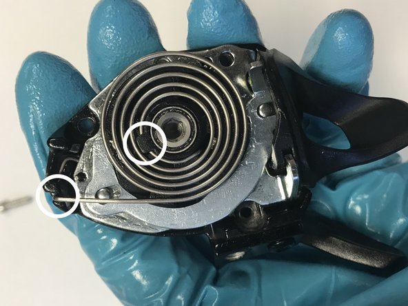 Reinstall the spring starting from the center: First locate the protruding tip of the inner coil into the corresponding hole on the spool. With the tip in place, gently pull the first inner coil over the  retention tab.