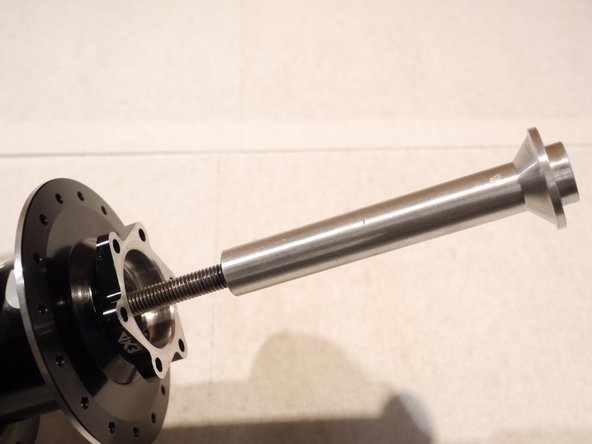 With the wings of the bearing removal tool set in the slots behind the bearing, insert the press rod, threaded rod and handle through the hub