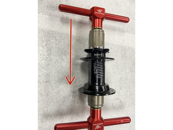 To install a new disc-side bearing, begin by gently centering the bearing in the bearing bore. Slide the bearing press drift onto the press tool and insert through the disc-side of the hub. Slide the bearing drift onto the press tool on the non disc side, and install the handle.Tighten the tool to press in the disc-side bearing.