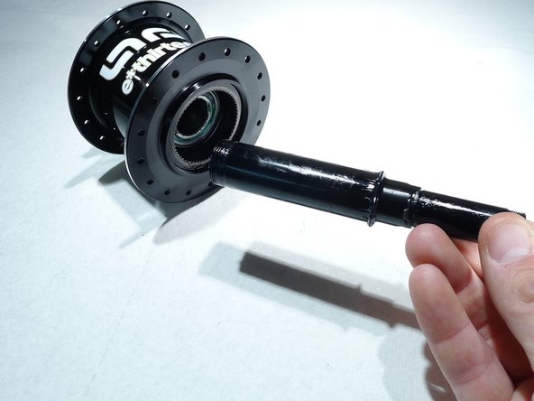 Start by lightly greasing the axle and sliding it back into the hub shell