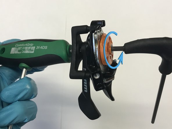 On the underside of the shifter, insert the T25 key thru the hole in the middle of the claw and into the T25 pivot bolt in the center of the bottom of the shifter.  On the top of the shifter, insert the 4mm into the screw in the center of the spool. The shifter should now be captured between your 4mm hex and your T25 torx.