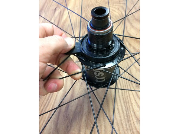 Pull the tab on the rubber ring, the ring will split at the slit and slide off the freehub body