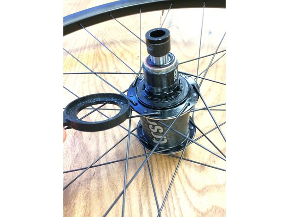 Pull the tab on the rubber ring, the ring will split at the slit and slide off the freehub body