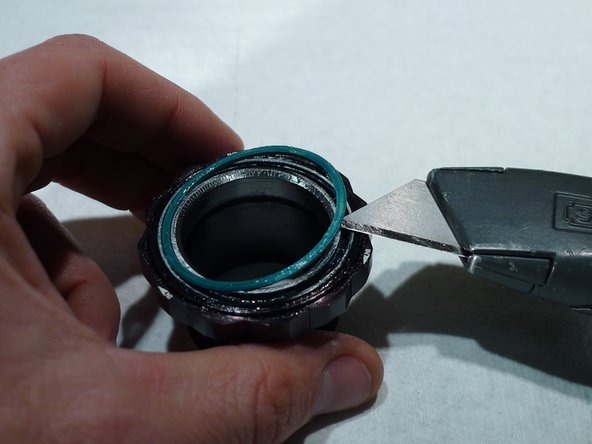 Remove the seal on the cartridge bearing by sliding a thin sharp tool such as a razor knife under the outer diameter of the bearing seal and lightly prying