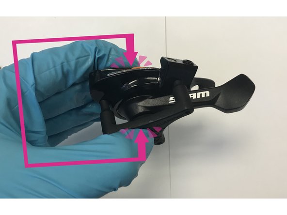 Flip over the shifter, and position the 3 prongs on the claw fixture into the recessed couterbores of the 3 screws you removed in the last step, while continuing to pinch the shifter assembly and body together.