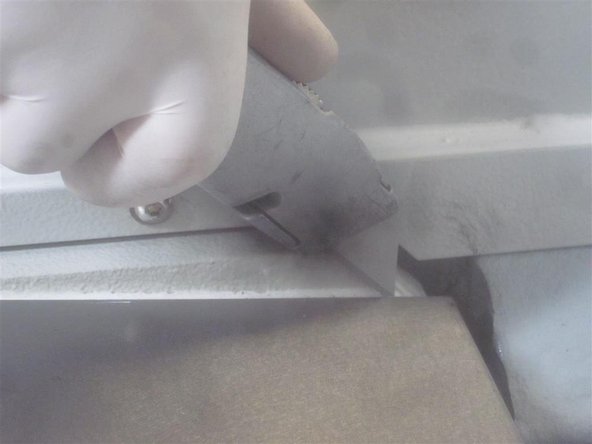 Using a utility knife, carefully cut through the white sealer located at the front of the bridge between the Y-Axis cover and the main base casting.
