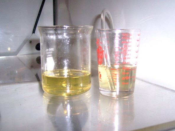 Slide one end of the flexible tubing over the oil line that lubricates the front spindle bearing. Temporarily place the other end of the flexible tubing inside the non-graduated cup to catch any oil from dripping out.