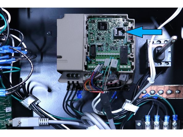 Power up the machine and open the electric cabinet door. In order to access the download port, 1 - Slide lock to the left with a small screw driver. 2 - Push down in the center of the lower cover and pull away from the drive. 3 - Push upper cover slightly to the left and remove it from the drive .