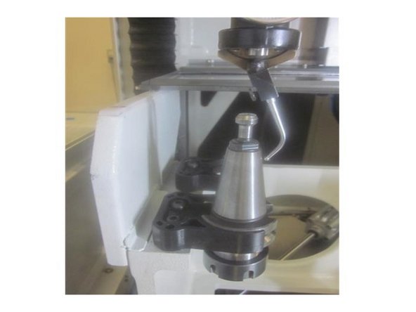 Using the Z axis lower the spindle guiding the indicator arm over the top of the tool holder allowing it to contact the tapered portion of the tool holder. Carefully adjust the spring tension on the arm so it has a slight load when contacting the tool holder.
