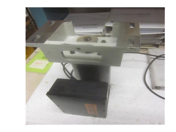 Carefully set the motor on a sturdy work surface with the cast mounting bracket facing up. Note the orientation of the bracket. The servo amp (box attached to motor) locates on the same side as the belt tension screw hole.