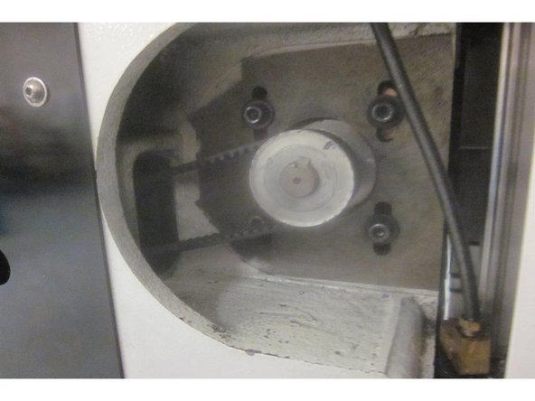 Remove the four ( 4 ) 1/4-20 SHCS attaching the motor to the casting. Remove the long 8mm belt tension adjustment screw from underneath the casting. The motor will be resting on the casting. Remove the belt from the pulley.