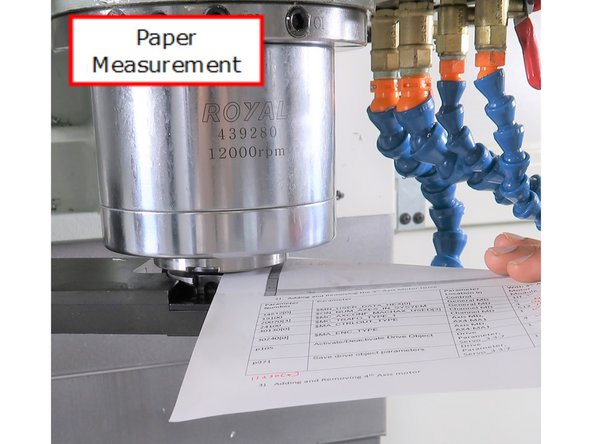 Jog the head down until you can just slide a 0.003-inch sheet of paper between the spindle tool holder and the round disk in the ATC arm, feeling a slight drag on the paper.