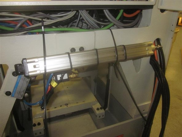 Using zip ties, roll up the cylinder, and tie it to the machine casting out of the way through the bottom of the electrical panel. Tie up the door cylinder to the casting as well.