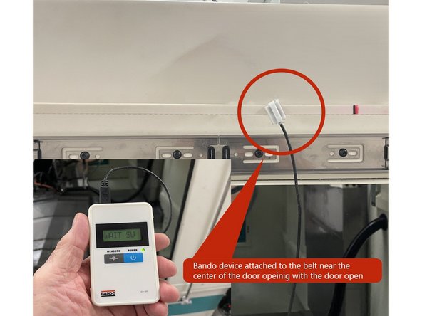 The belt now needs to be tensioned. To do this attach the sensor from the Bando Belt Tension Meter to the belt halfway between the (2) pulleys with the door in the open position. See Photo 1.