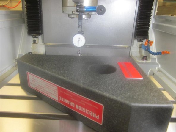 Set the tenths indicator as close to the center of the spindle as possible. Place the stylus of the indicator along the RH side of the stone at the rear corner. Jog Y back and forth while adjusting the stone, until it reads 0 along the full length of the stone.