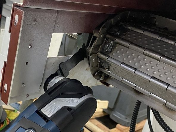 With the sheet metal cover from behind the sprockets removed you should have access to the cotter pin in the belt. Remove the cotter pin and if needed reposition the belt so that the main pin can be removed. (With no tension on the belt you should be able to move it by hand.) Using a small drift punch remove the main pin.