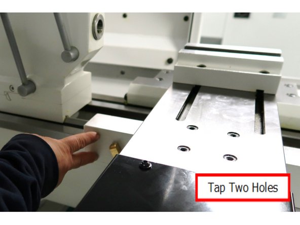 From the rear of the lathe, tap two holes for M6x20 (25B) SHCS into the back side of the saddle as shown. Parts are supplied in the kit. There is no location marked on the lathe. The important aspect is to make sure both screws are tapped straight into solid metal to support the coolant system while in use.