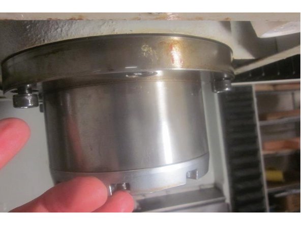 Raise the Z axis and loosen the six (6) 8mm screws that retain the spindle in the motor housing. Look for shims noting their orientation. Remove the shims and set aside. Remove the four (4) 8mm screws on both the left and right side of the spindle. Leave the front and rear screws ( 6 and 12 o'clock) in place.