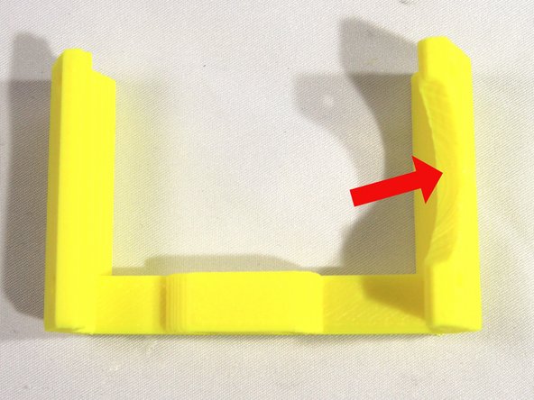 Trim off the corner pads (used to hold the fan bracket to the bed when it was printed) with an X-acto knife. Note the circular cutout indicated by the arrow - clean any plastic residue from it too.