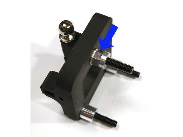 Press one of the eccentric spacers into the back side of the carriage in the side with the single hole. The black marked surface should face out as shown in the photo.