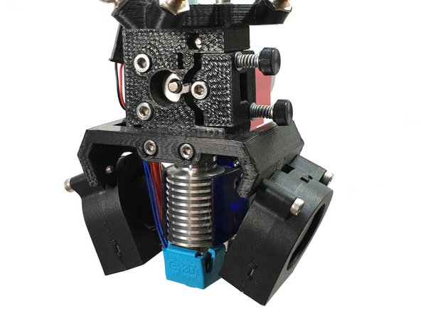 Install the heat exchanger fan shroud  with the fan positioned under the stepper motor as shown in the first photo. Note the blue arrow - it shows the bottom of the heat exchanger fan shroud aligned with the first fin on the heat exchanger.