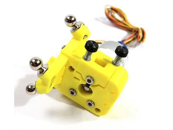Using the two idler tension screws you prepared earlier, install the idler to the extruder body as shown.