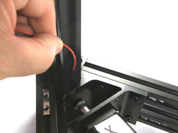 Thread the black connector into the slot and down and out the bottom of the X tower column as shown.