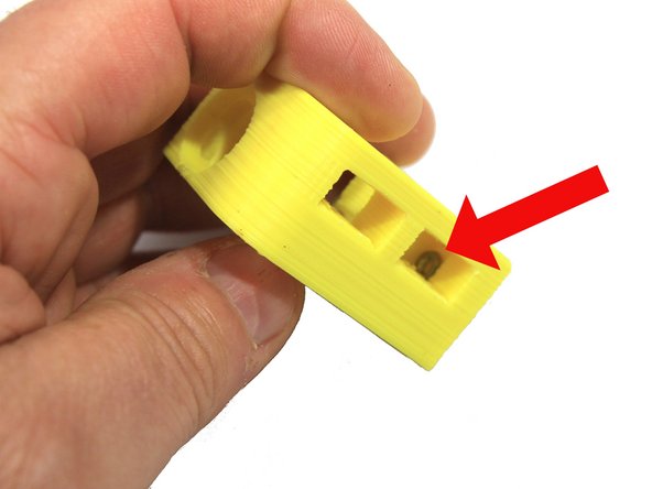 Insert an M3 nut into the slot inside the extruder body cavity. Use a small screwdriver to push it into position as shown. Check the alignment of the nut by looking thorough the hole. It it is not properly aligned, wiggle it into position with the screwdriver.