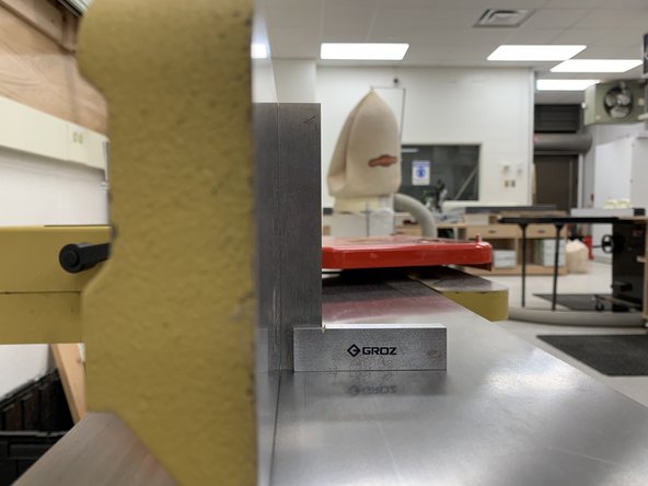 Adjust angle by turning adjustment wheel, checking angle with a machinist square for 90° or a protractor for any other angle.