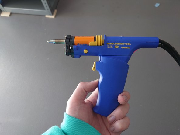 The desolderer is connected to a pump on the Hakko system, and will heat up the tip so that solder can be first melted, then sucked into the cardboard filter behind the desoldering tip.