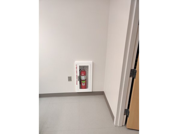 The fire extinguisher is located on the far wall beside the closet.