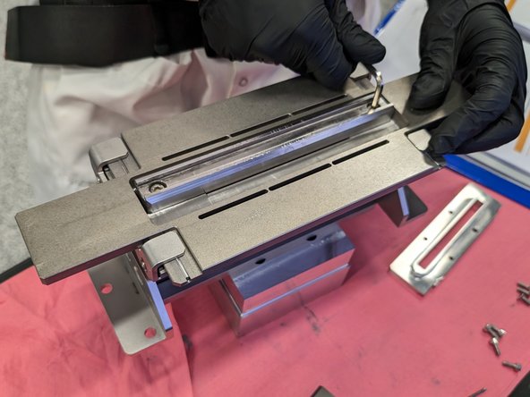 Next we will remove the guide rails for the wiper blades. Loosen the two screws that lock the rail in place. There are springs? under this part so make sure it doesn't fly away.