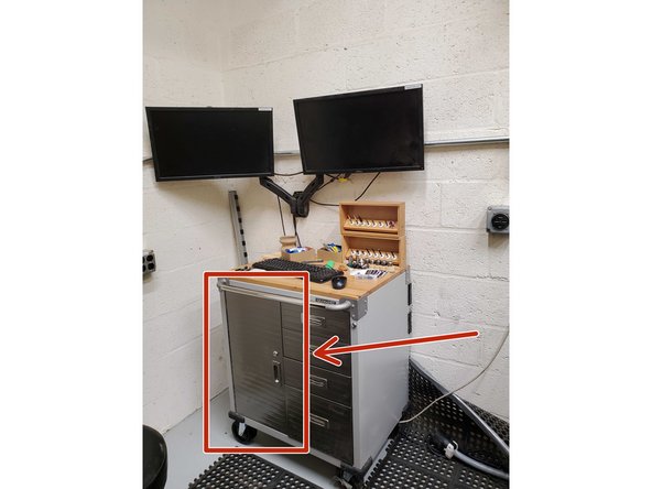 The computer is located inside the cabinet to the left of the machine.