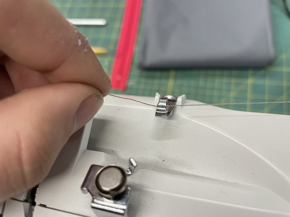 Route the thread through the system. there is a picture on the top of the machine to show how. (follow the dashed line)